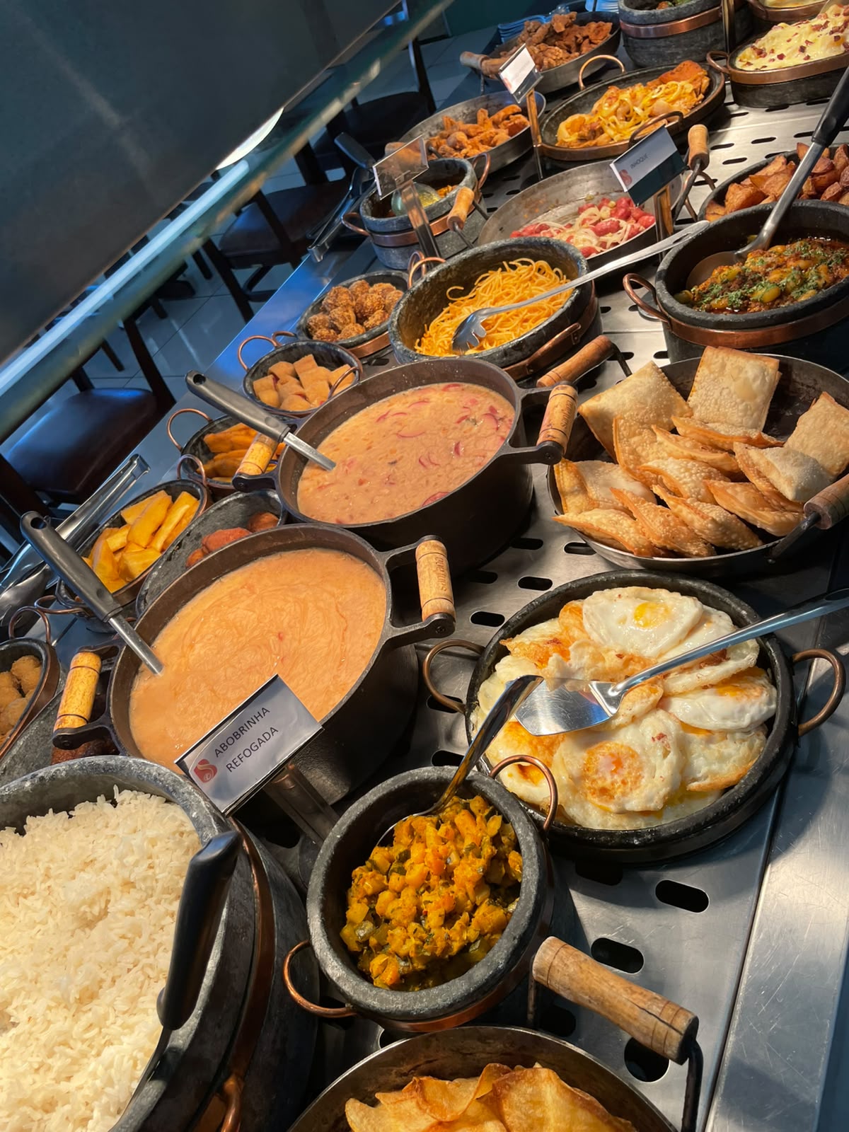 Linha quente do buffet com abobrinha refogada, massas, pastéis e ovos